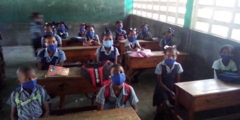 Haitian students physically distanced and wearing masks at school desks