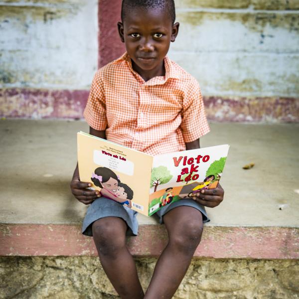 Boy reading a book outside of the school