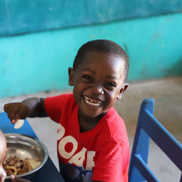 Image of young boy smiling at the camera while eating