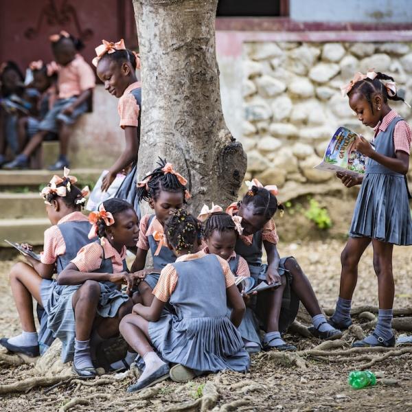 Group of young girls reading by a tree