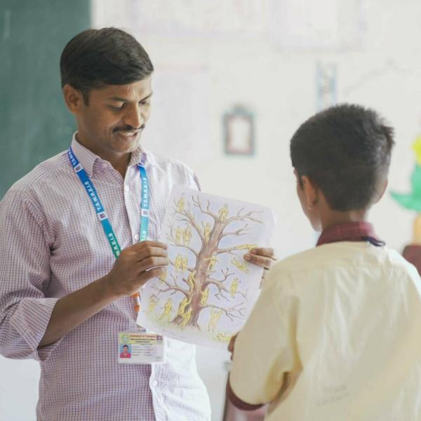 Image of teacher (left) showing a student (right) a drawing of a tree