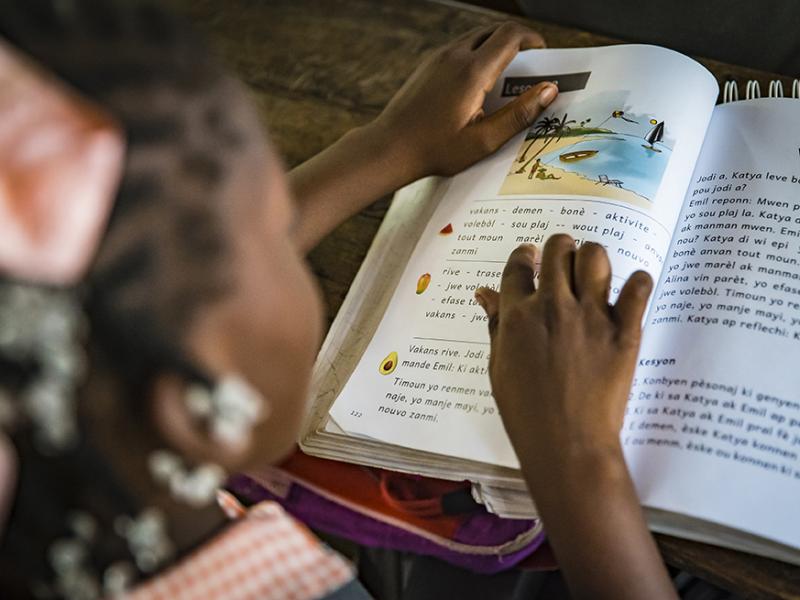 Student reading from classroom library in Haiti